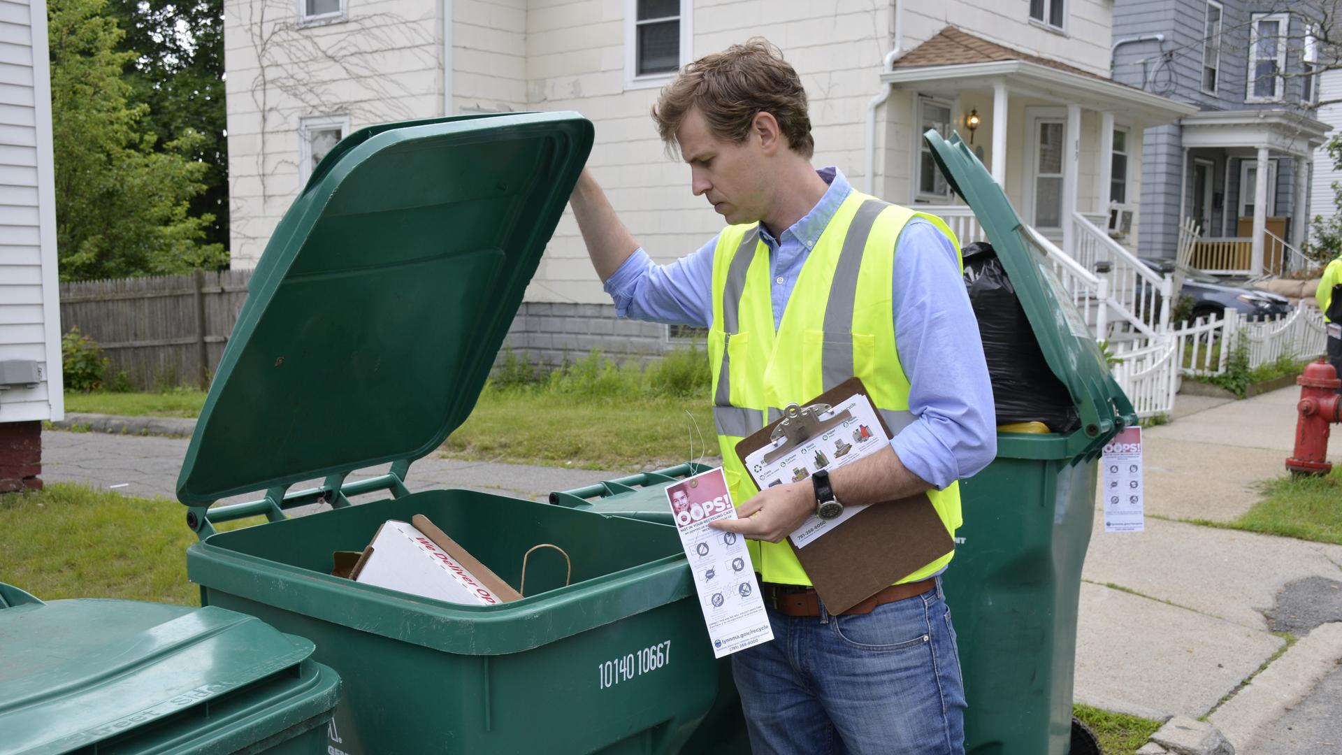 Cody Marshall, with The Recycling Partnership, looks through a recycling bin in Lynn, Massachusetts. His organization is working with cities across the nation, helping them educate residents on how to recycle better.