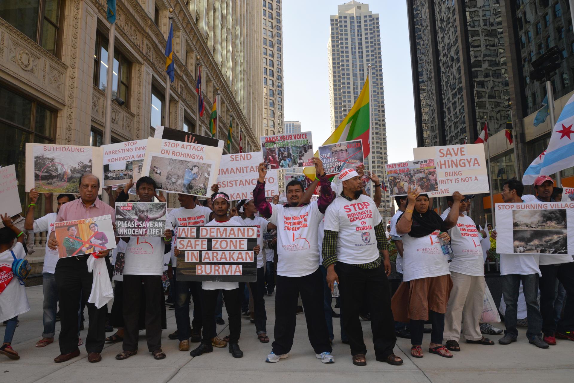 A wide shot of a people holding signs in front of a downtown Chicago skyscraper.