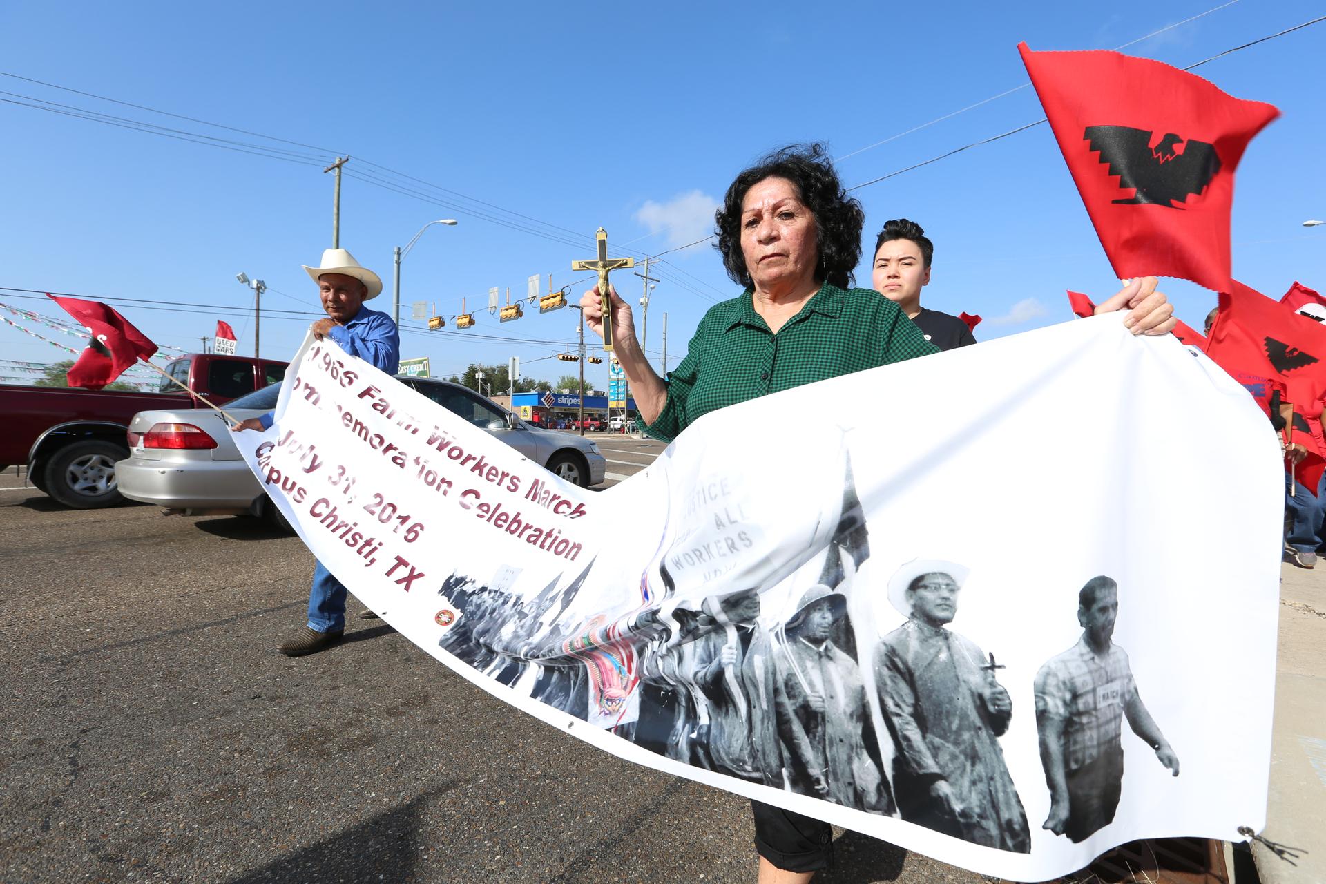 Woman on street holds sign showing farmworkers marching in black and white photo