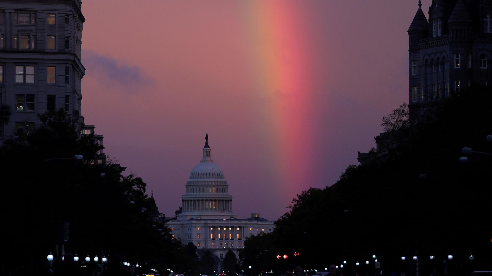 A rainbow stretches across the sky above the US Capitol dome