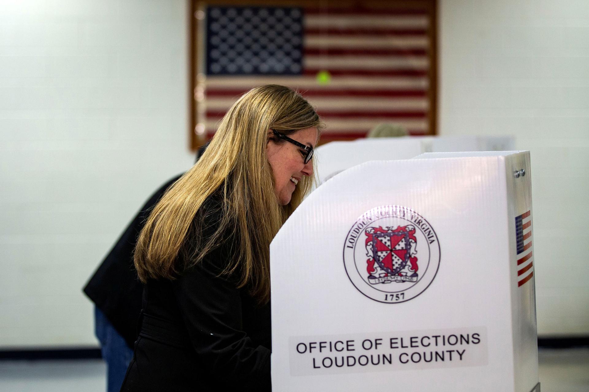 A woman uses a voting booth that says Office of Elections Loudon County.