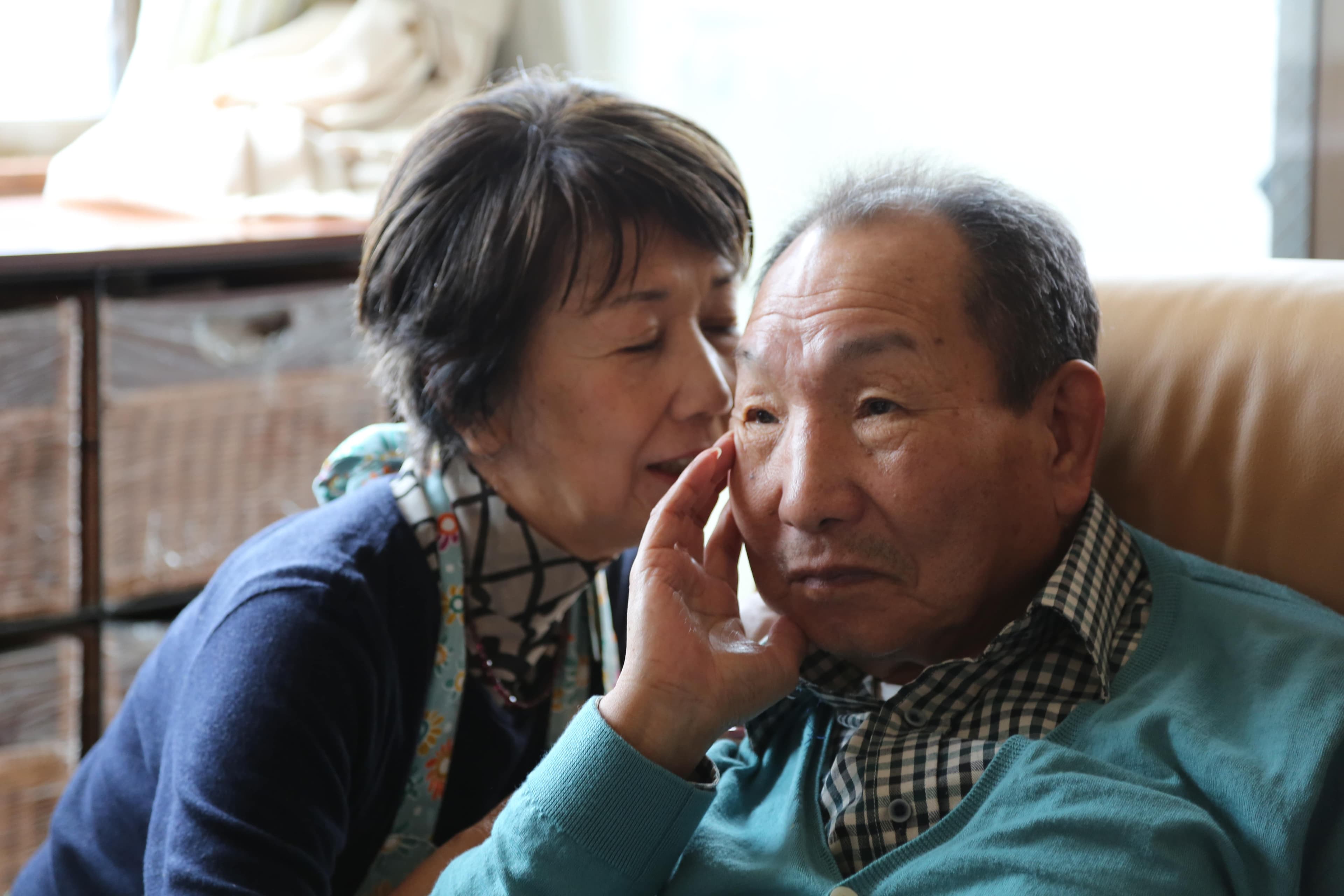 a woman whispers into a man's ear