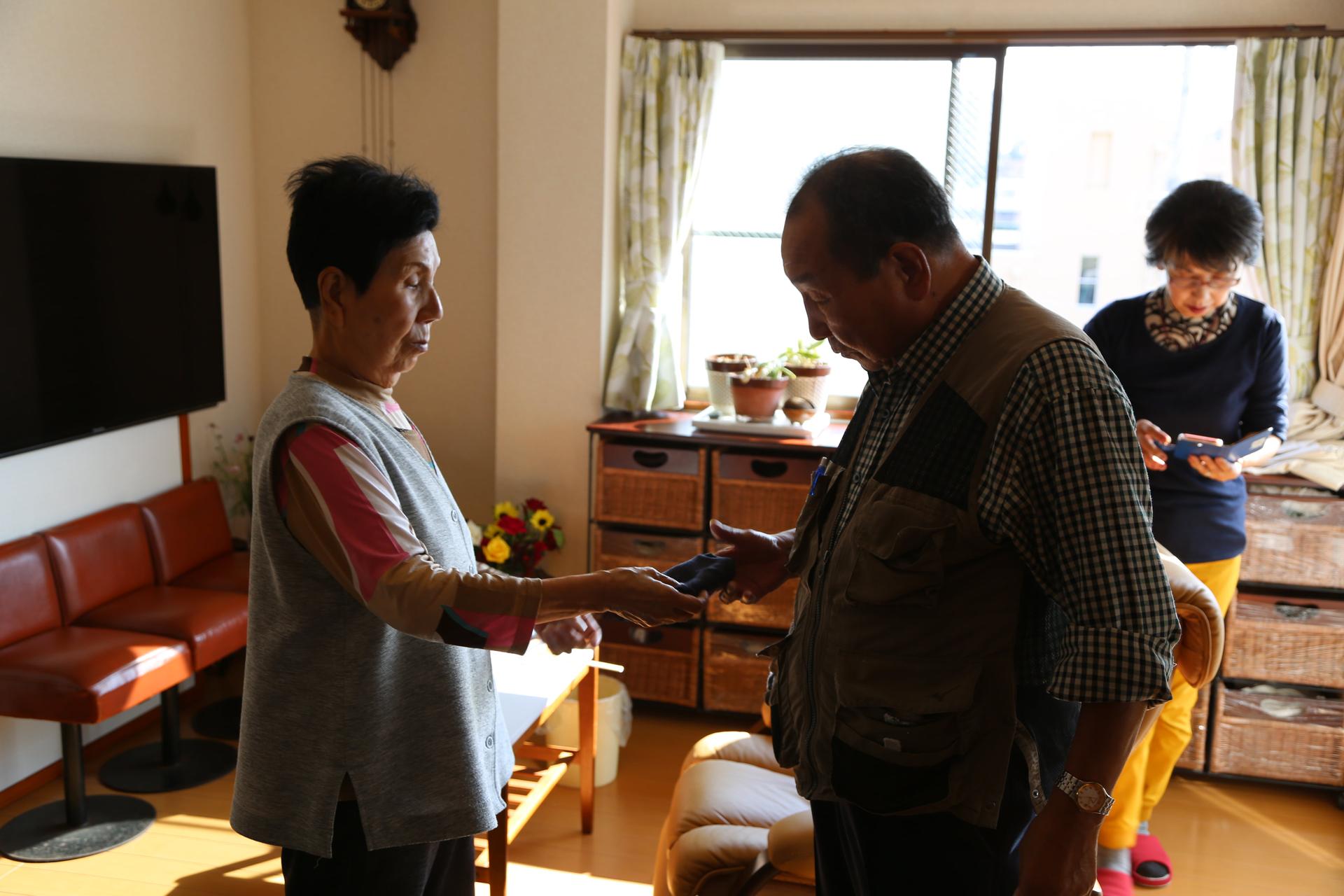 Hideko Hakamada hands her brother Iwao a handkerchief inside her house