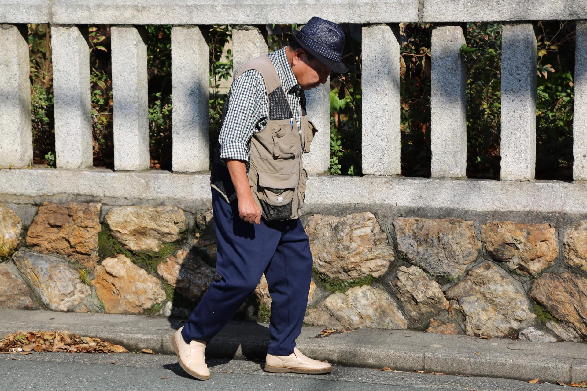 Iwao Hakamada walks in front of a fence
