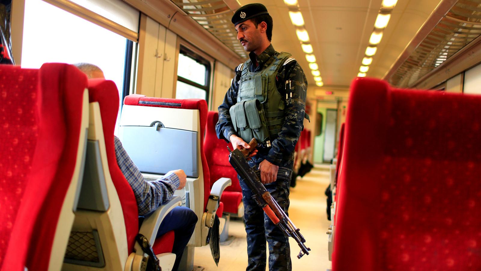 An Iraqi policeman stands guard in a passenger cabin with red seats on the way to Fallujah.