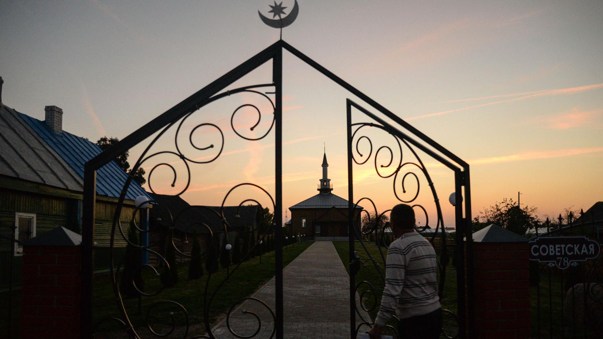 A sunset with the silhouette of a mosque and man approaching