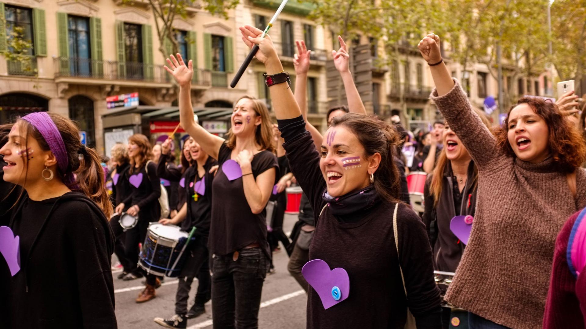 A street is shown filled with many women with arms raised rallying against prostitution.   