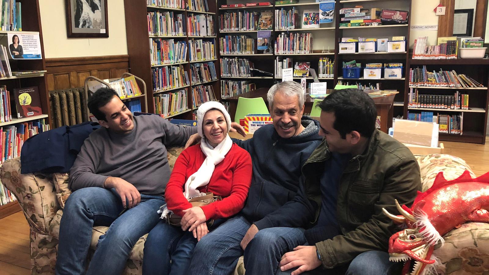 Iranian family reunites on a couch in a library.