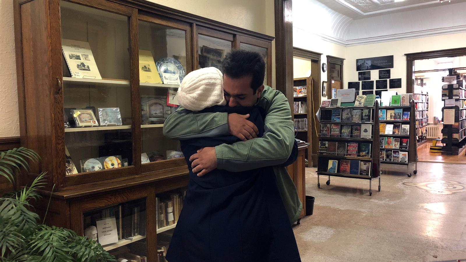 A mother and son embrace in a library. 