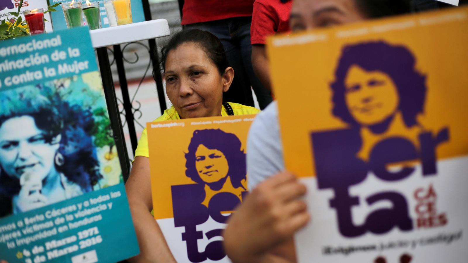Demonstrators hold signs with Berta Cáceres' face outside a court.
