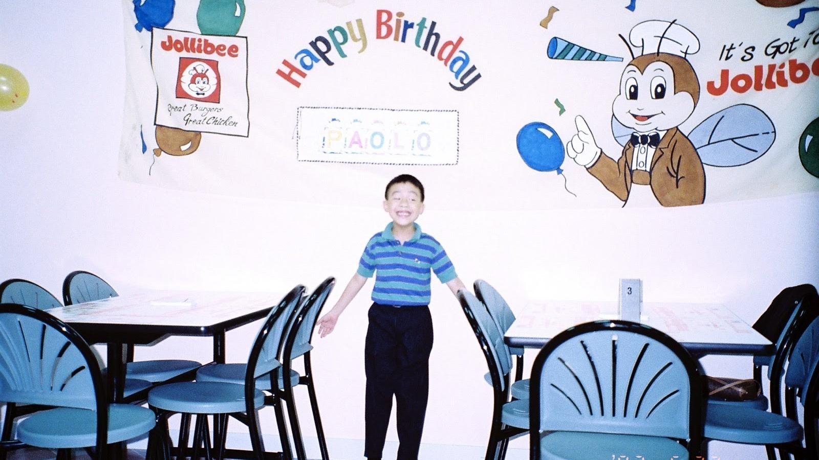 A 7-year-old stands in a Jollibee restaurant with birthday decorations.