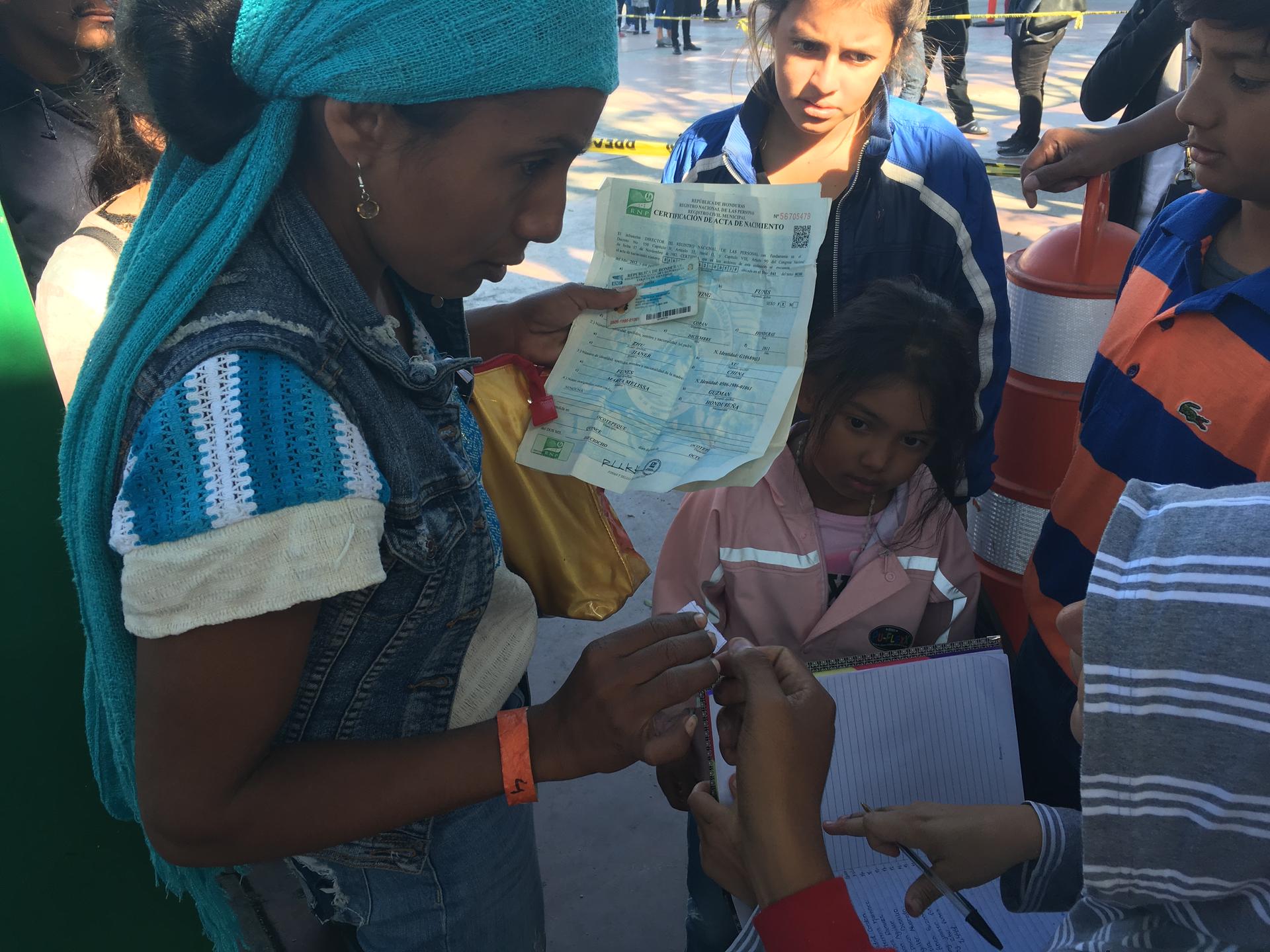 A mother and her kids registering their names in the notebook at the port of entry so they can get on the list to apply for asylum in the US. 