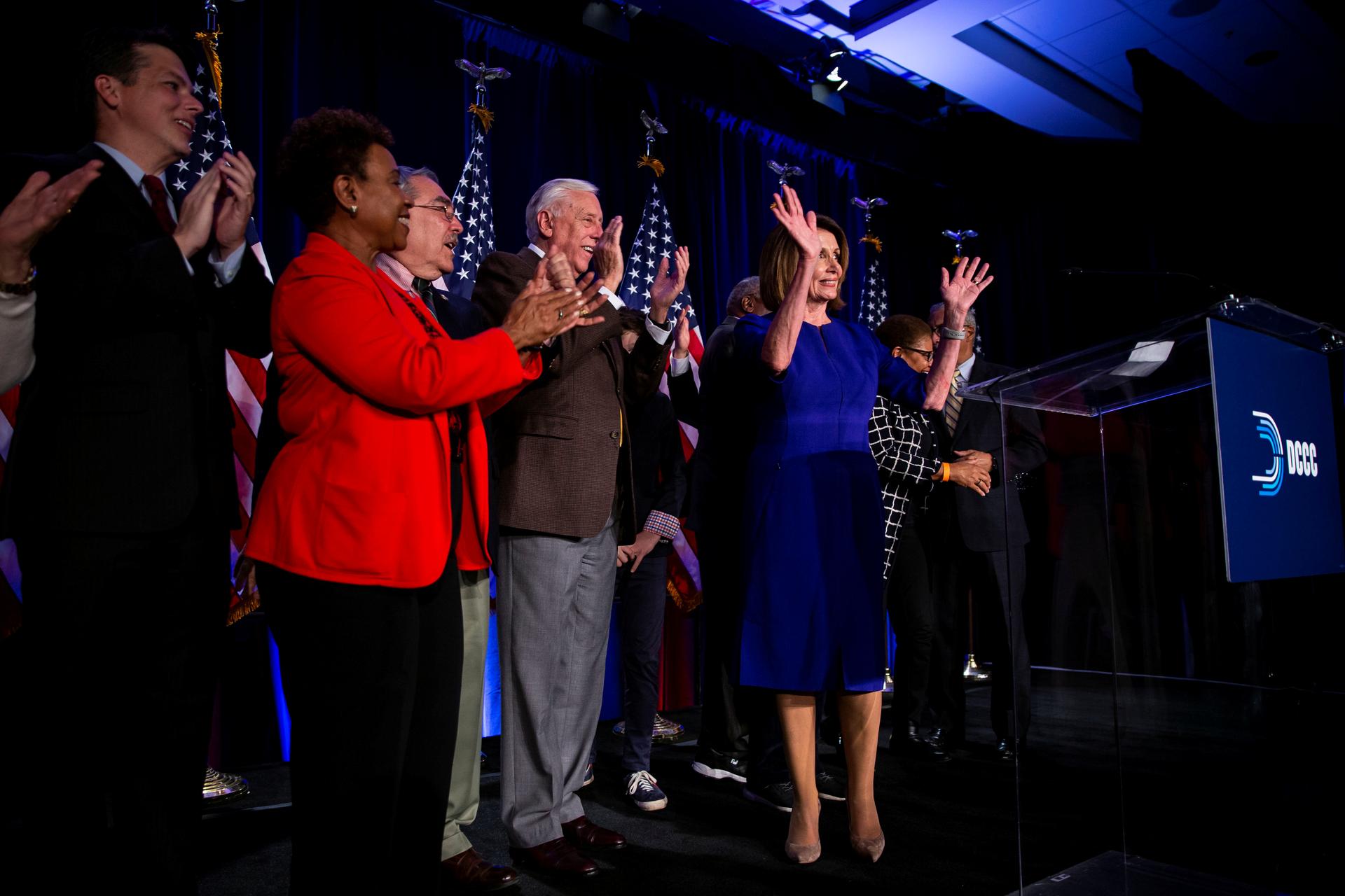 several house democrats celebrating on a stage after their majority house win