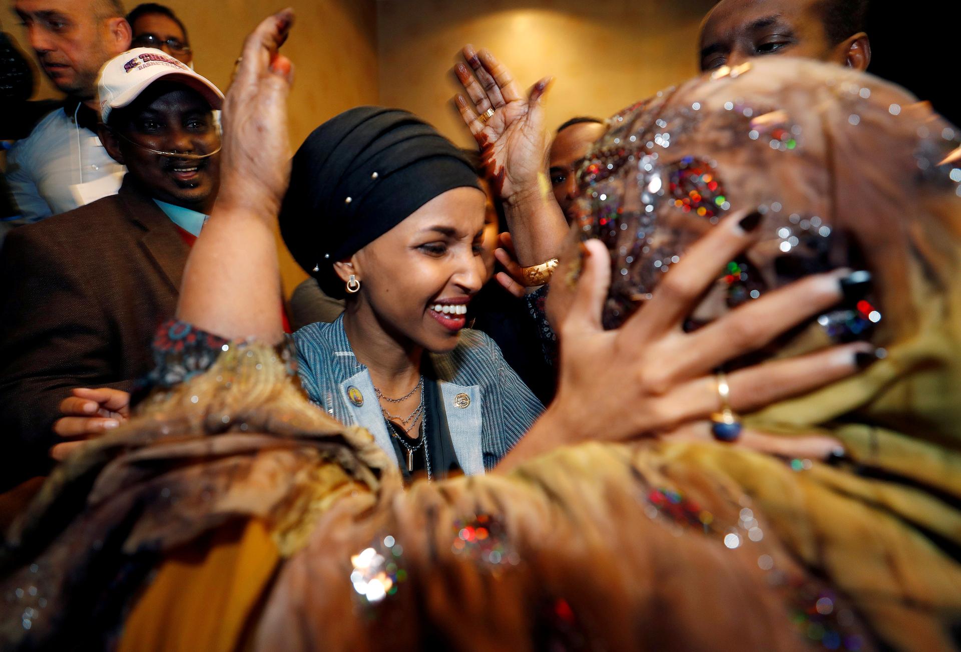 Ilhan Omar clasps her husband’s mother's face in her hands as she smiles 