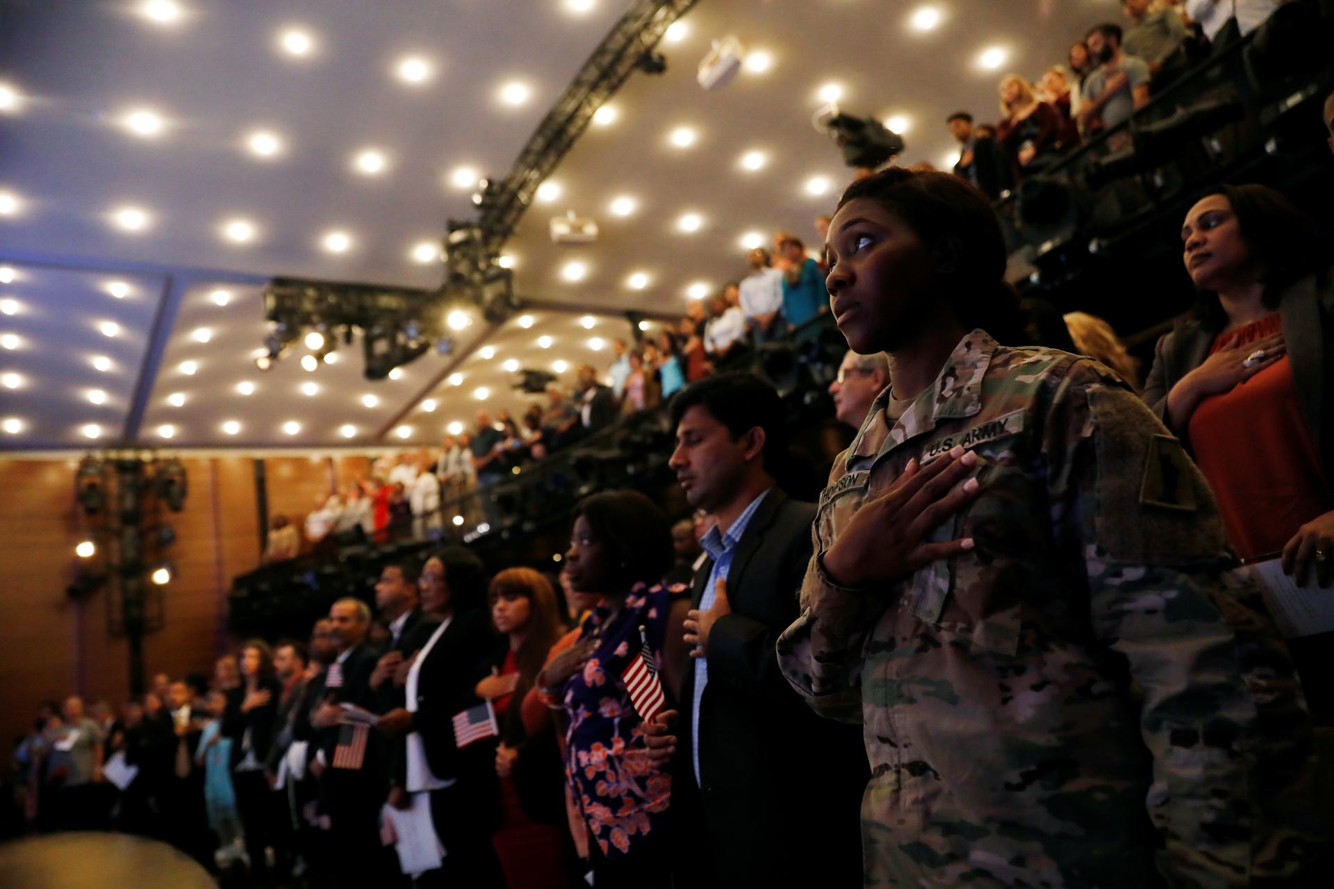 New citizens stand during the National Anthem at a U.S. Citizenship and Immigration Services naturalization ceremony
