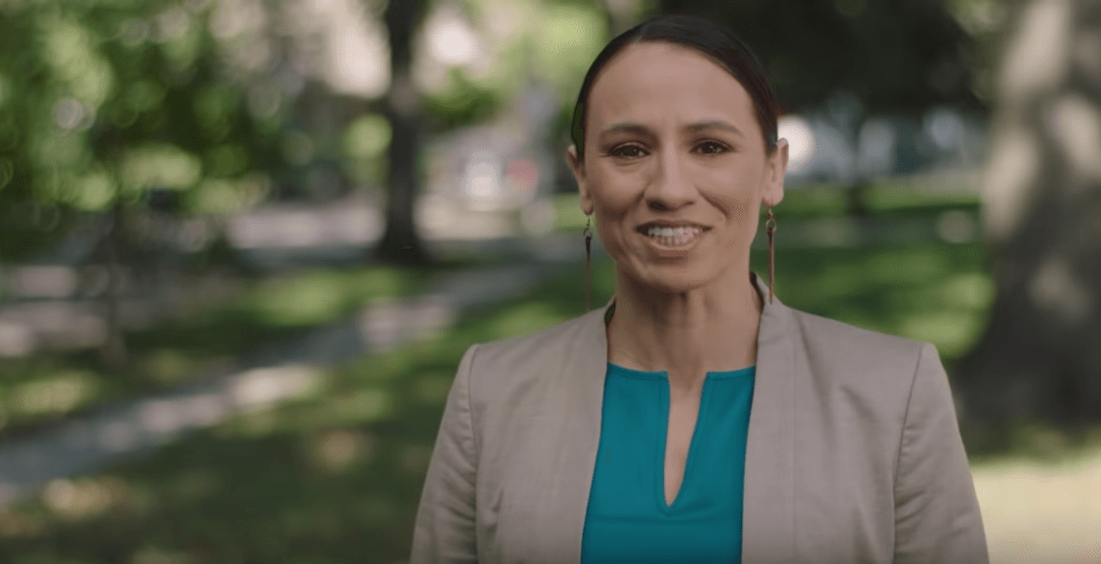 Sharice Davids stands under trees and smiles