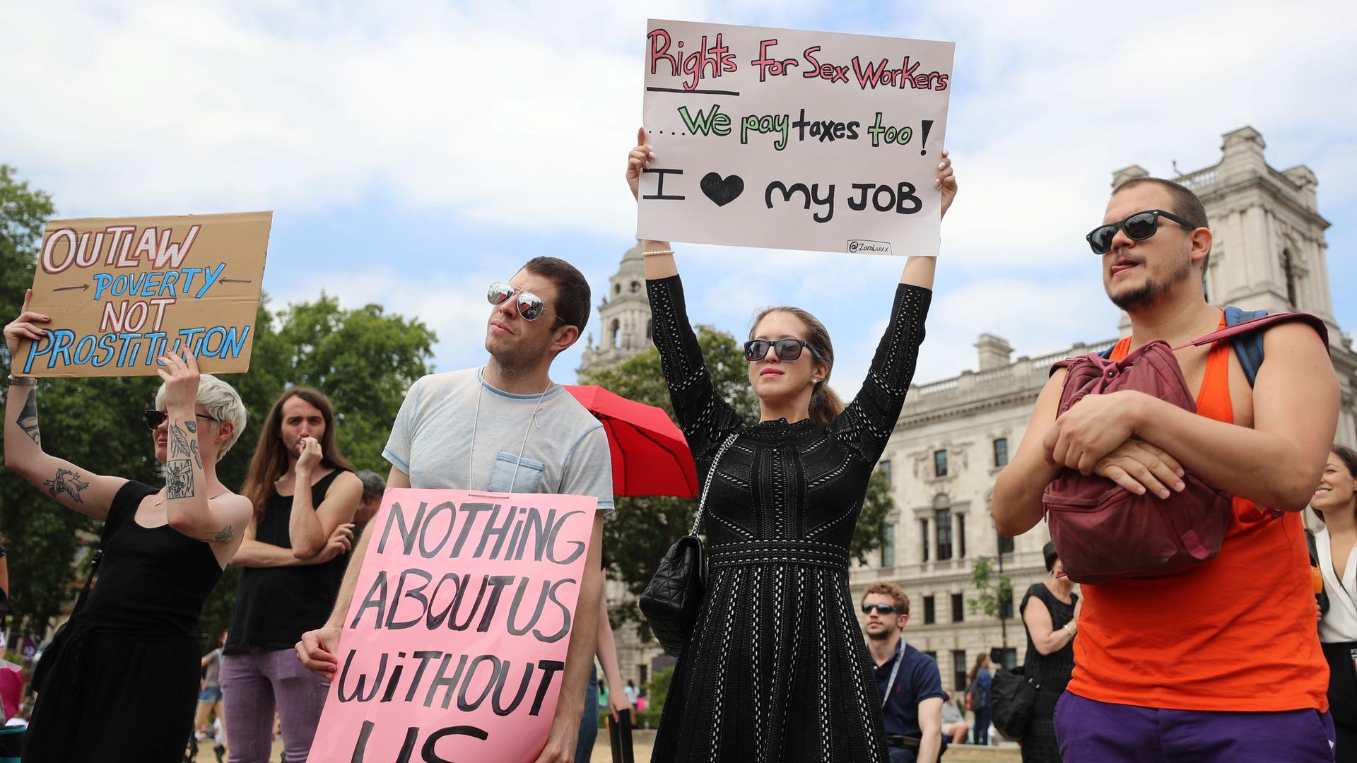 People stand with signs supporting sex worker rights -- "end poverty, not prostitution," and other signs.