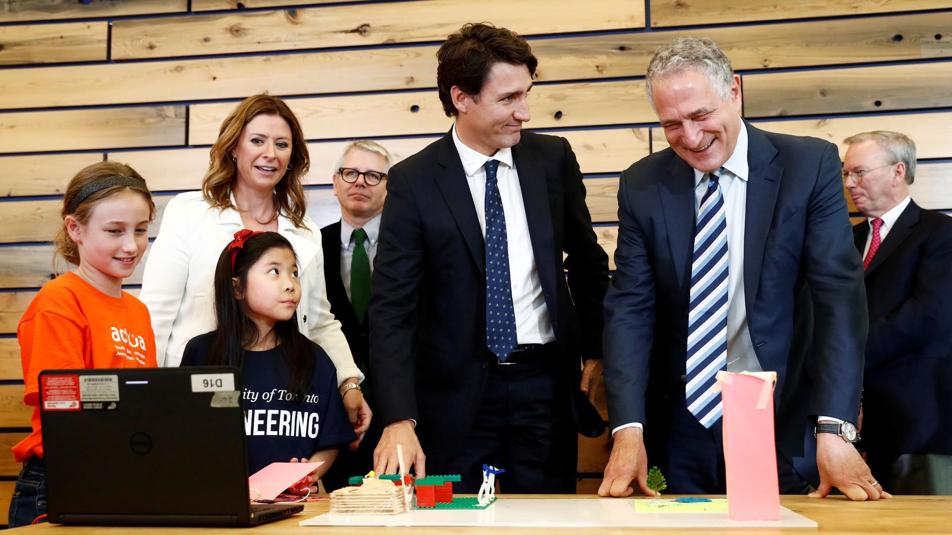 Canadian Prime Minister stands at a table surrounded by others.