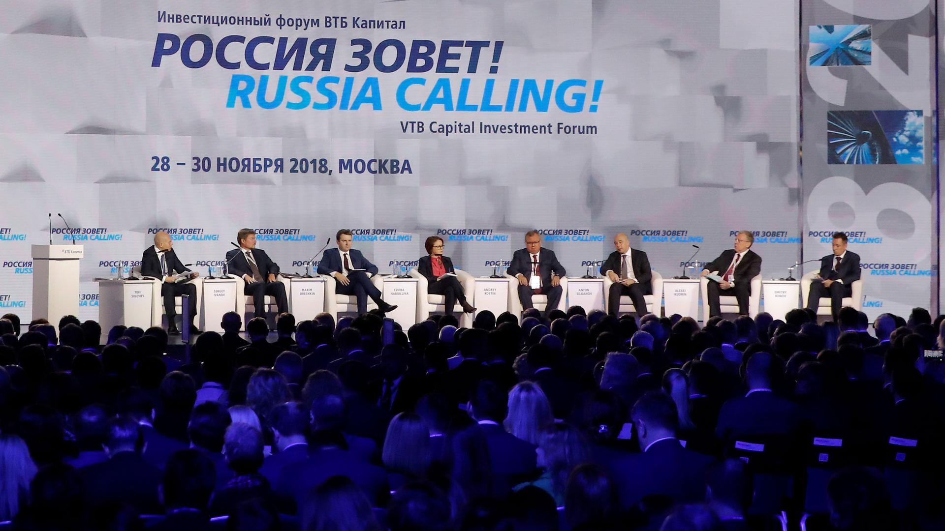 A line of people sit on a panel in front of a large crowd. Behind them, the backdrop says "Russia calling!" 