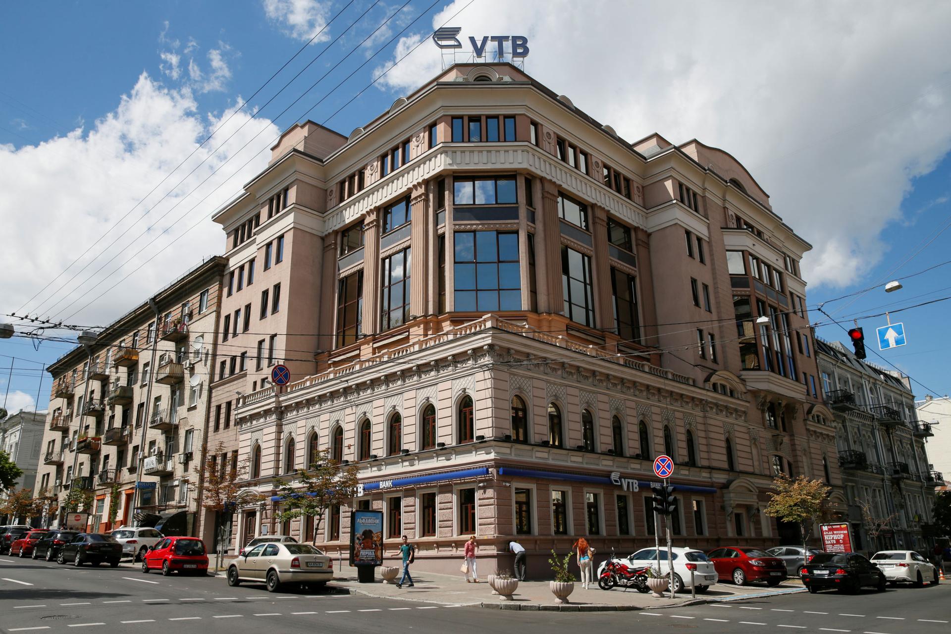 A older brick building is on the corner of a street. Atop the building is the logo for VTB bank.