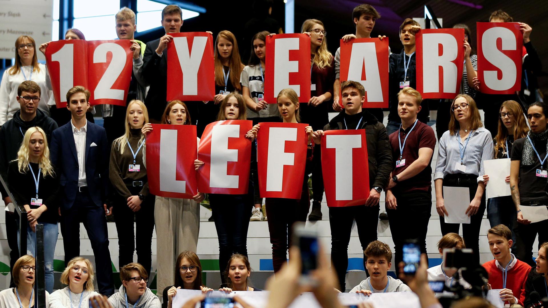 A group of school children hold signs that read "12 years left"