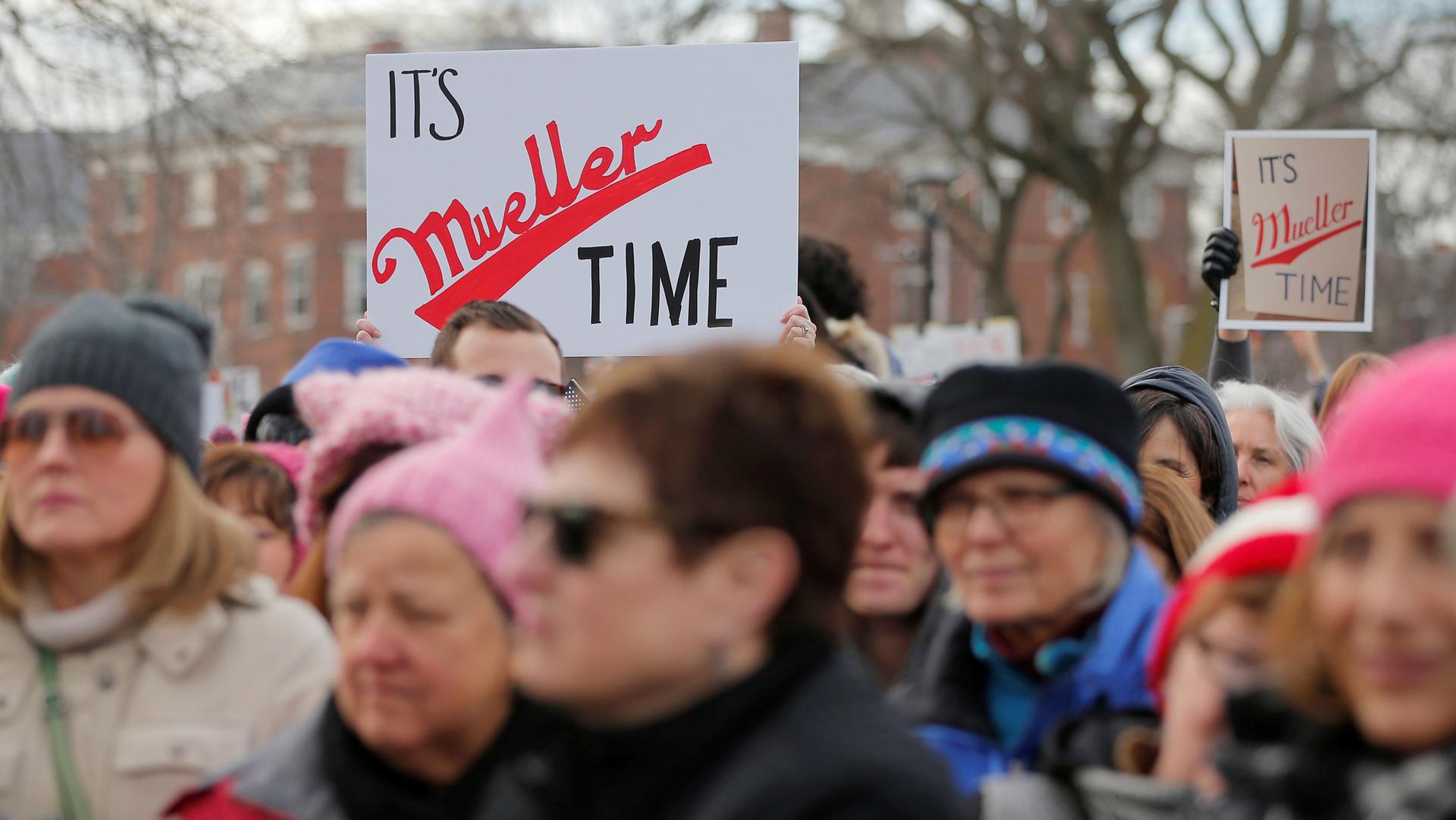 Protesters hold signs that say "It's Mueller time" riffing of Miller Lite's "Miller time" advertisements. 