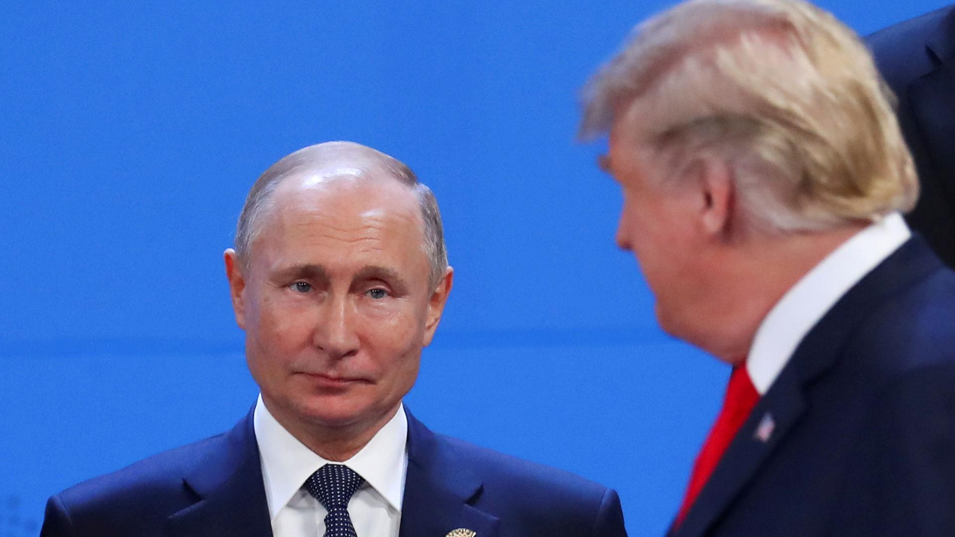US President Donald Trump is shown out of focus in the near ground with Russia's President Vladimir Putin seen in focus in the background.