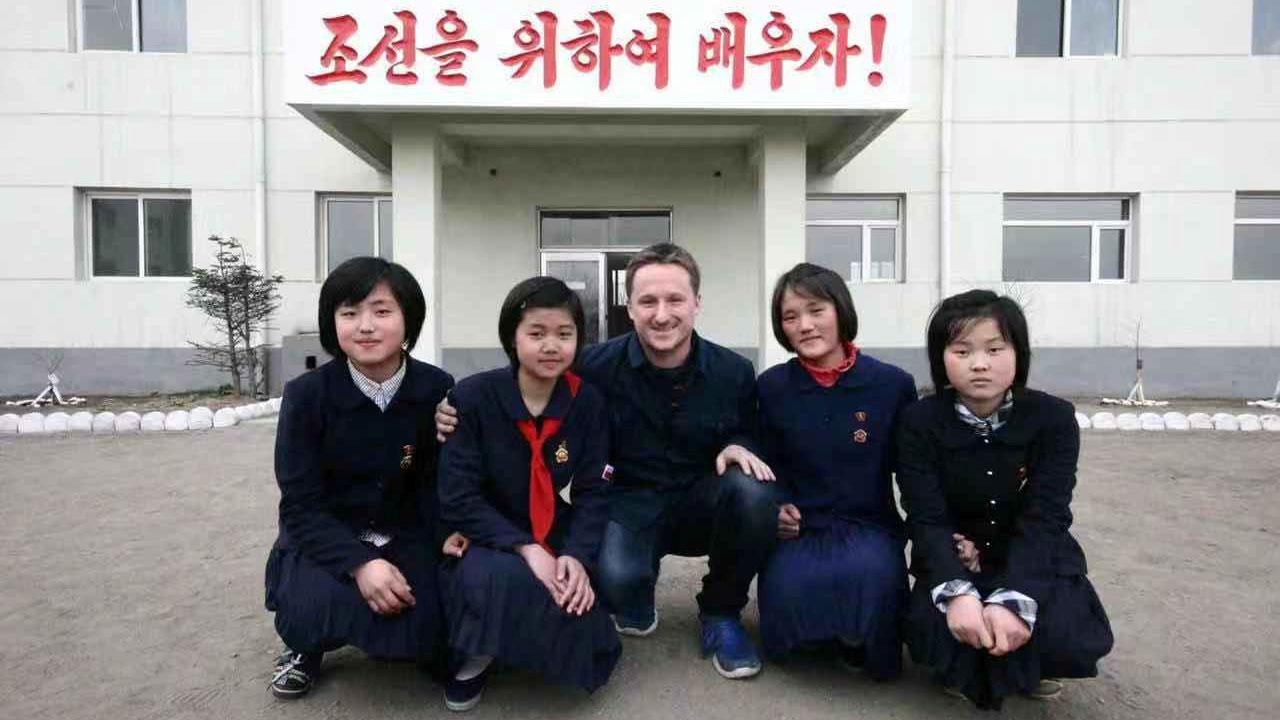 Canadian businessman Michael Spavor is shown kneeling along with several your Korean school girls in uniform in North Korea,