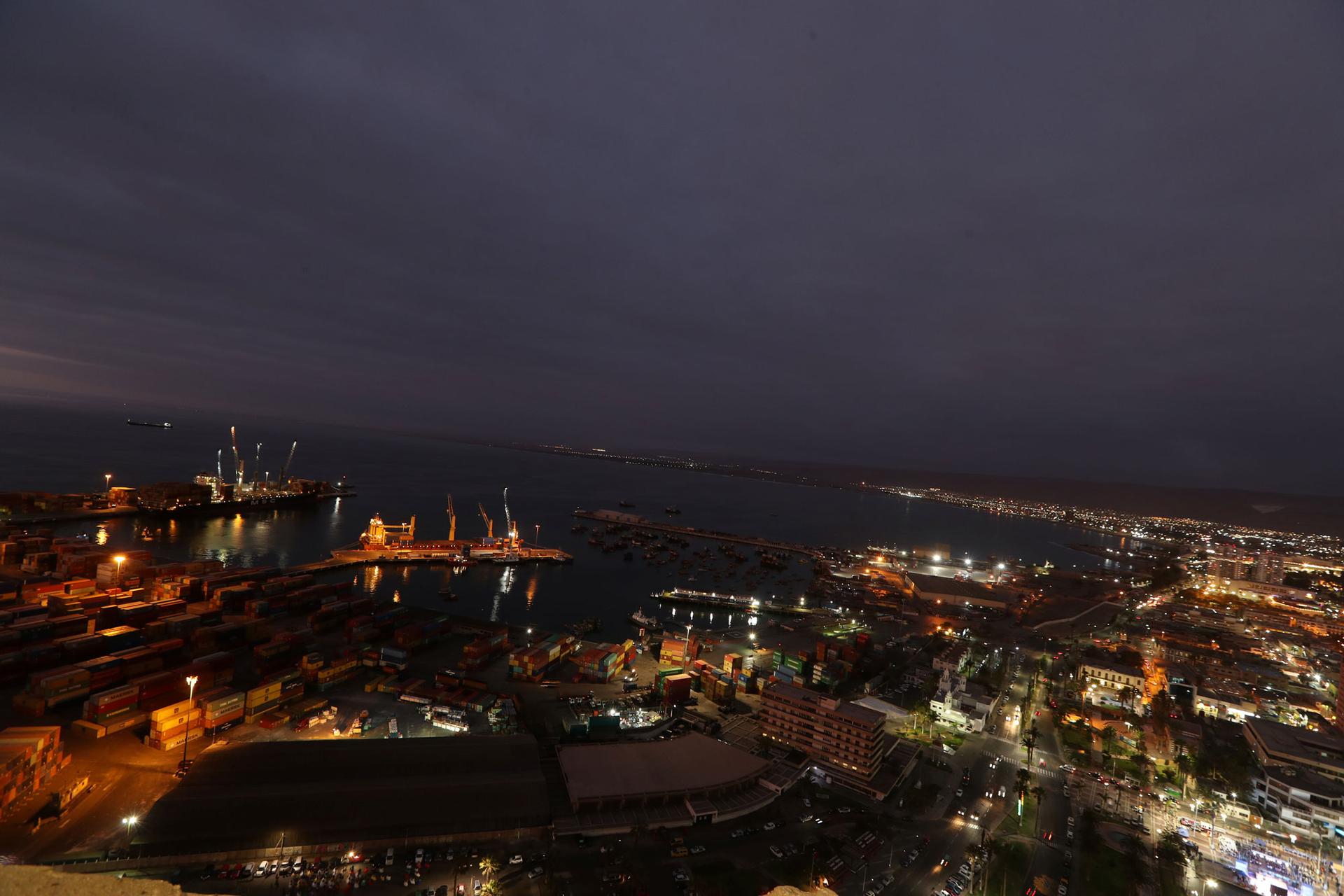 In this wide angle photo taken at dusk, Arica city is shown with shipping facilities on the water.