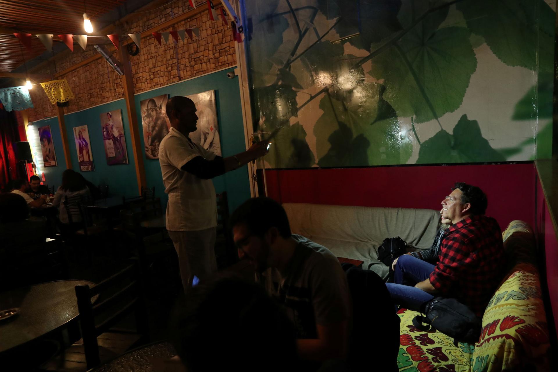 In this darkly lit restaurant, Venezuelan migrant Enrique Miller takes a picture using a flash.