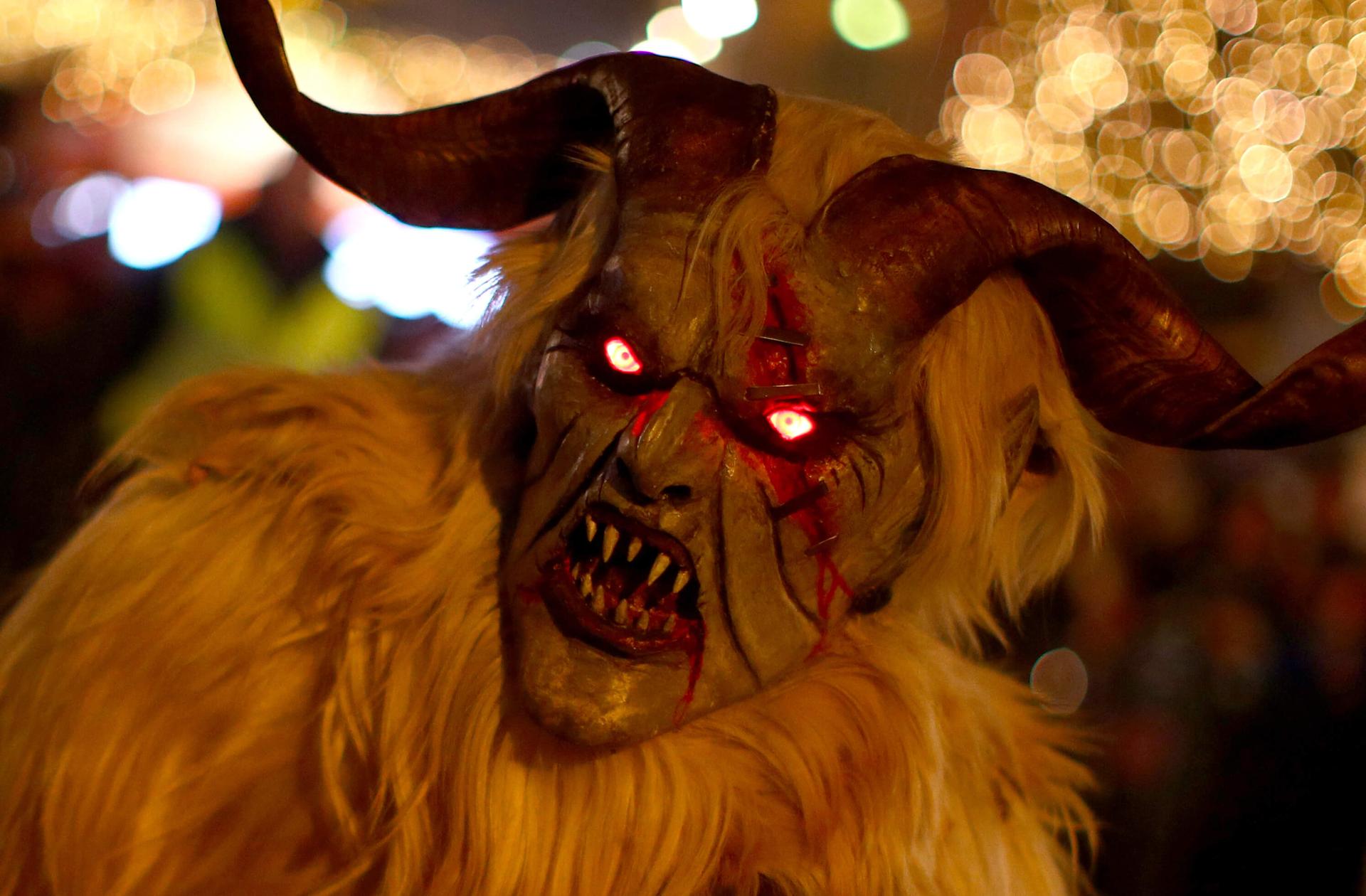 a closeup of a Krampus mask with glowing eyes