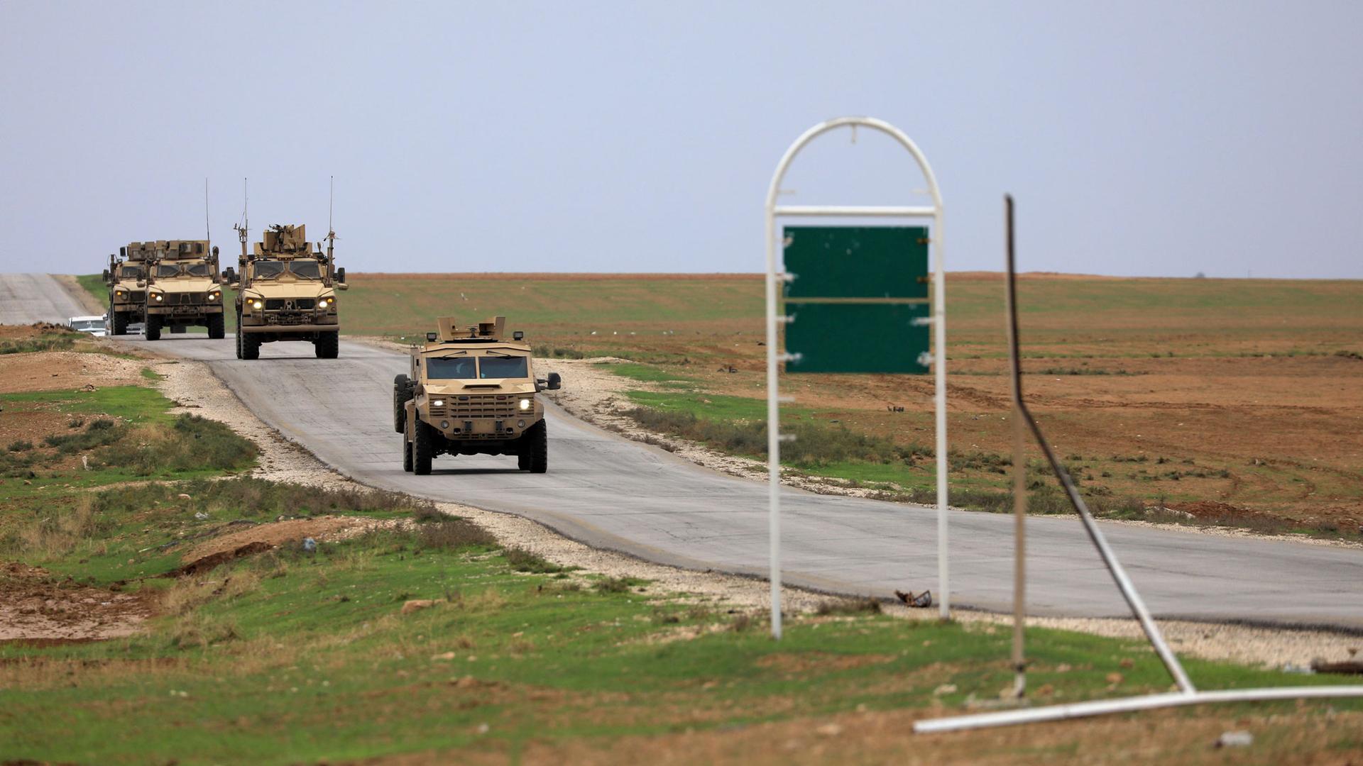 US troops driving armored vehicles are show driving on a road patroling near the Turkish border in Hasakah, Syria, 2018.