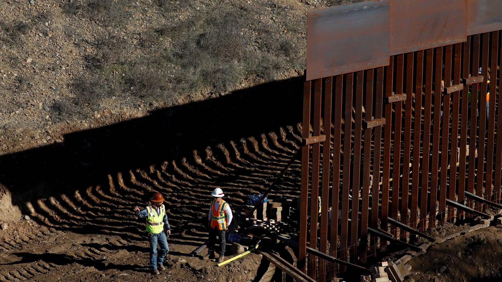 Workers construct border wall. 