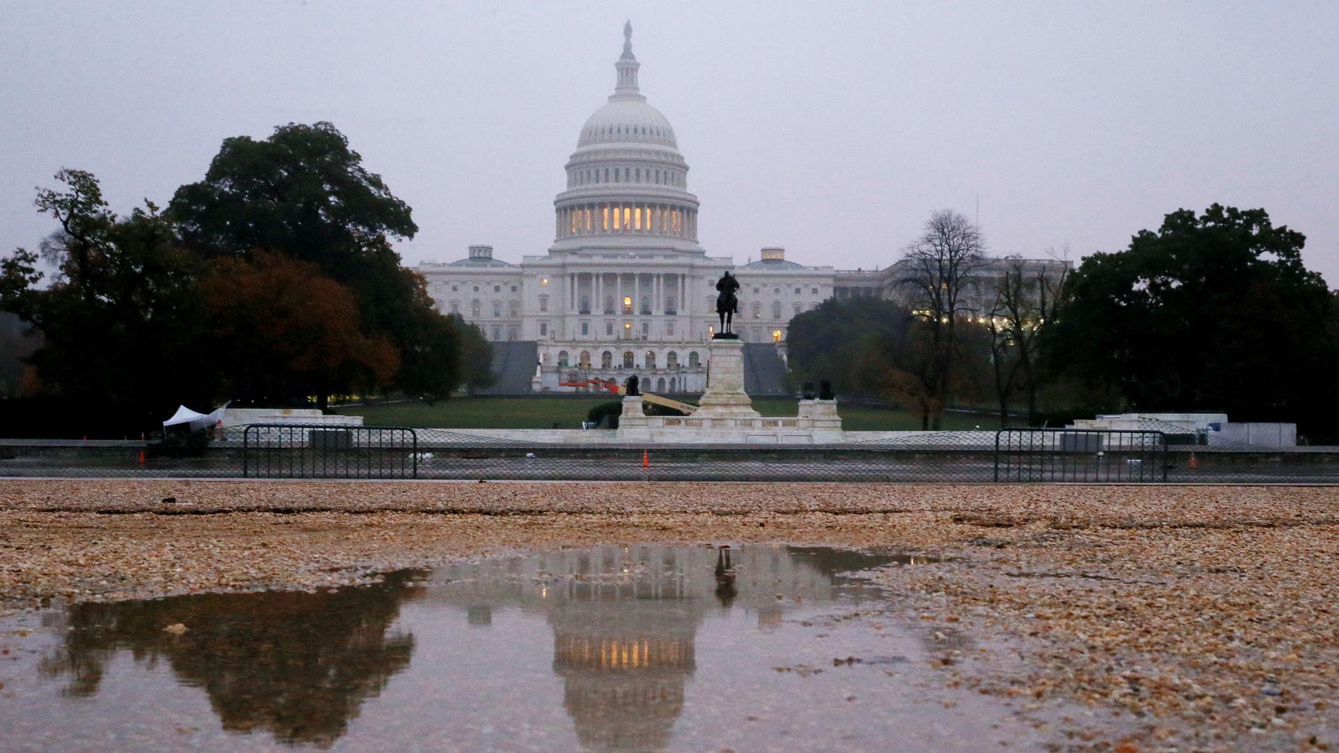 US Capitol building is seen reflected in a puddle at sunrise on the day of the US midterm election 