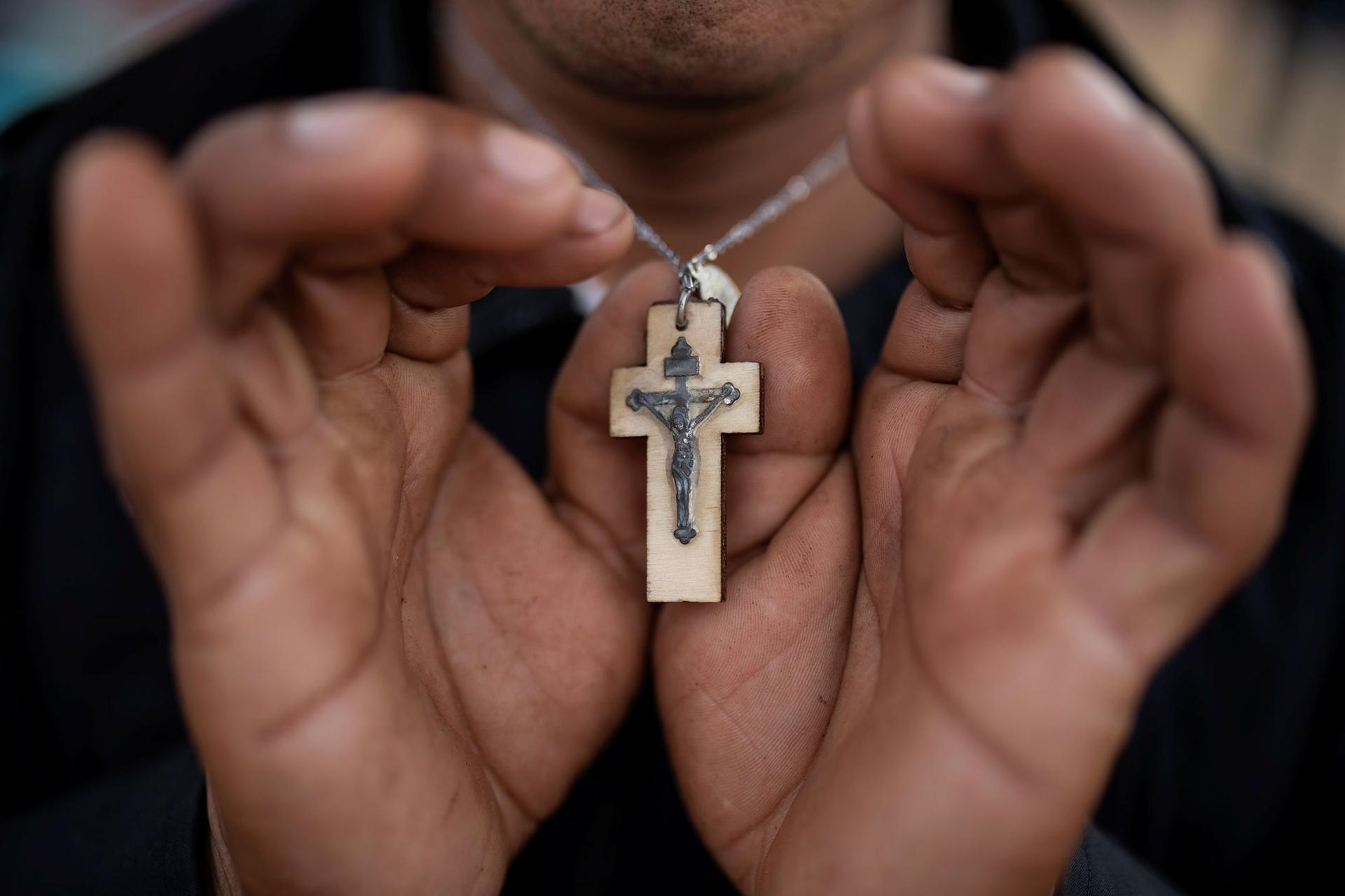 A close-up photography of Nicolas Alonso Sanchez holding his wooden cross.