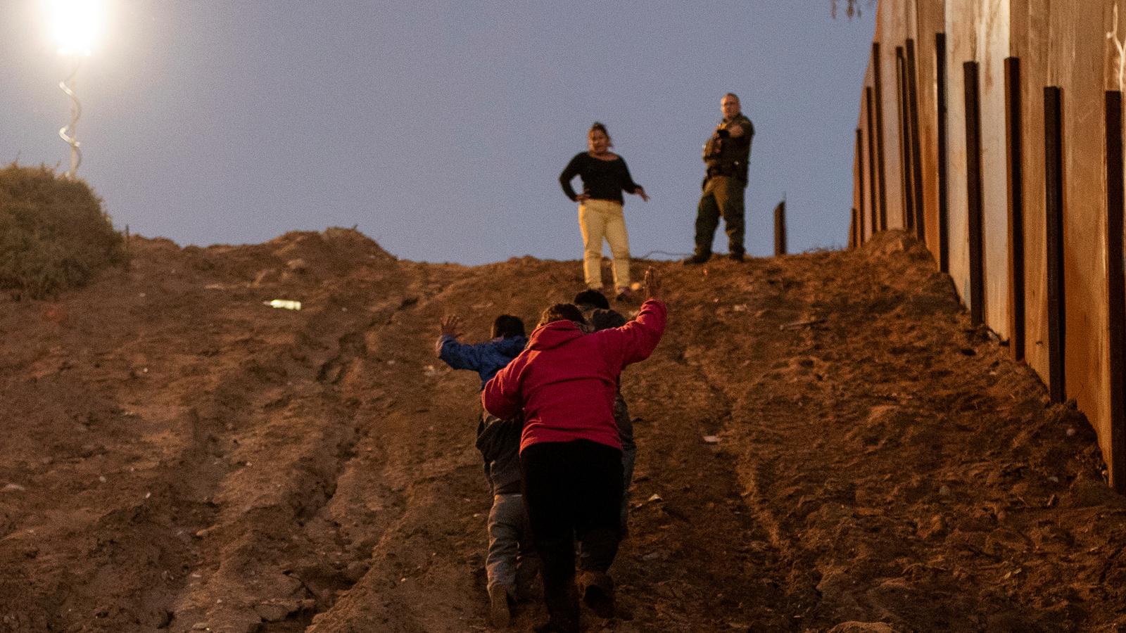 Migrants put their hands in the air as they surrender to a US Border Patrol agent. 