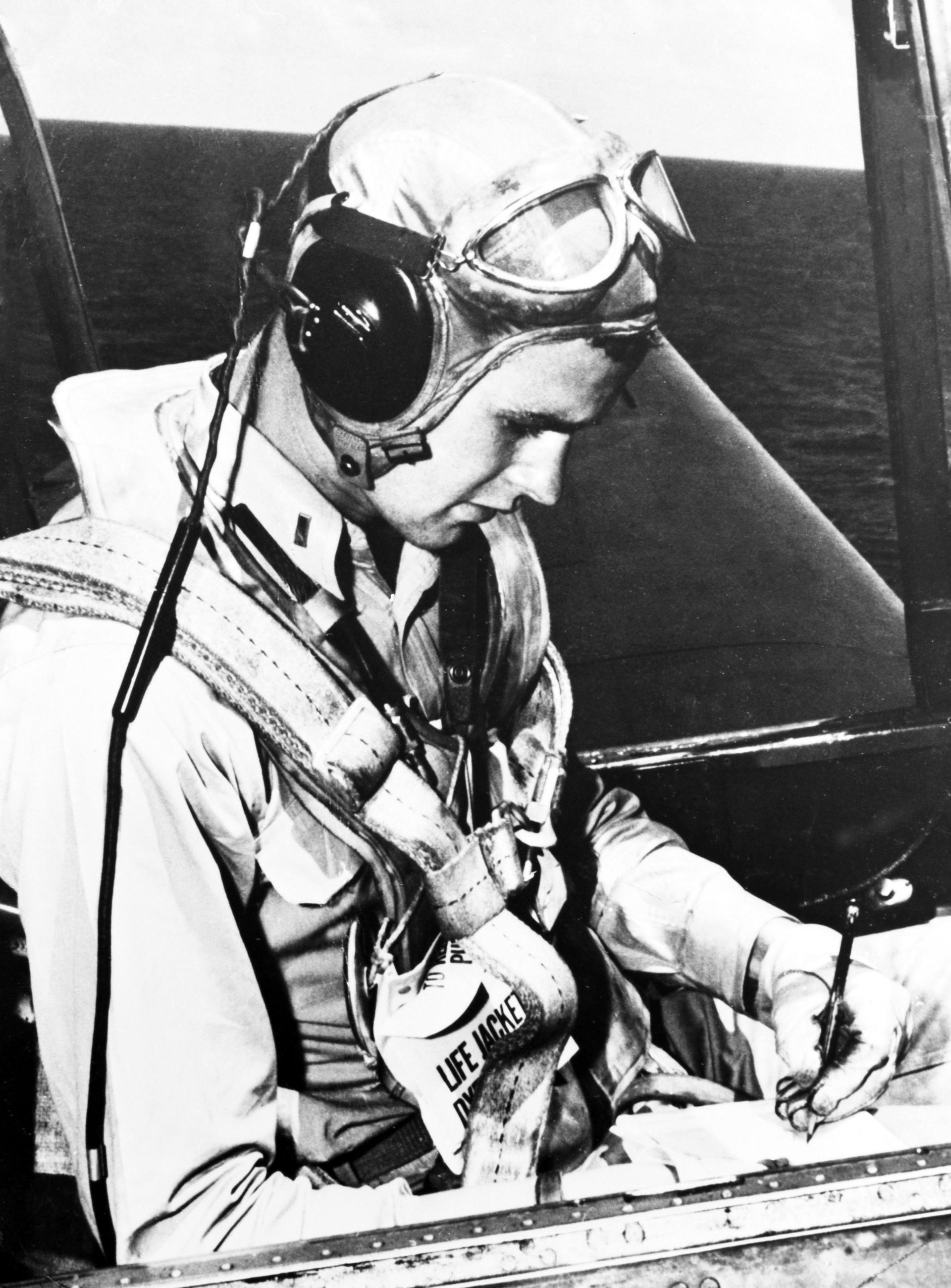 A young man in a pilot suit sits the cockpit of a WWII era Avenger plane