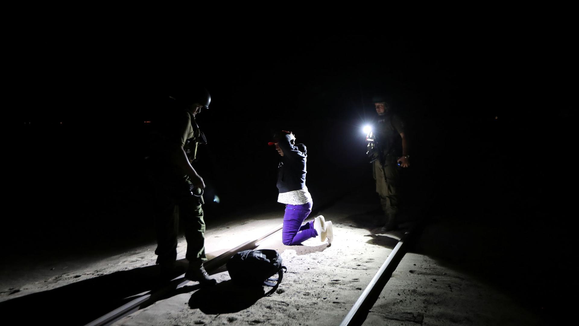 Migrant Yoniel Torres is shown wearing purple pants and handcuffed at theChilean and Peruvian border in Arica, Chile.