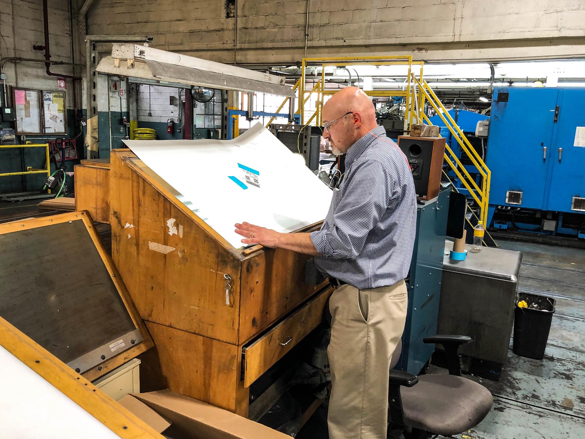 Mohawk paper engineer Paul Graver examines a new batch of paper looking for impurities.