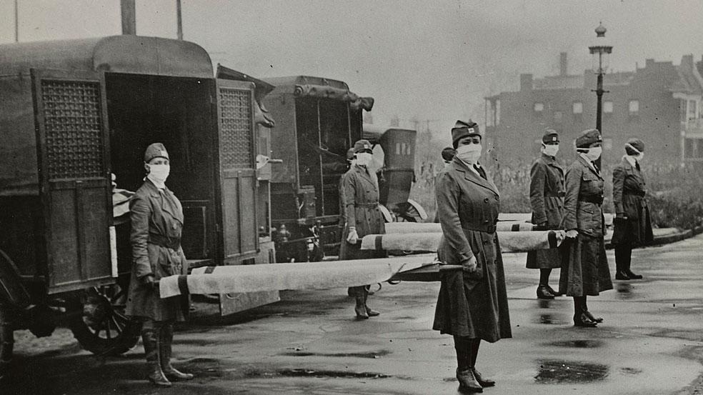 Women in uniform hold stretchers in front of ambulances in this historic photo.