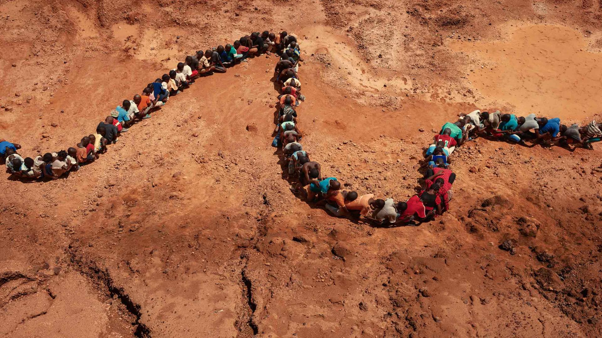 People form a line like a snake on the bed of a dry riverbed
