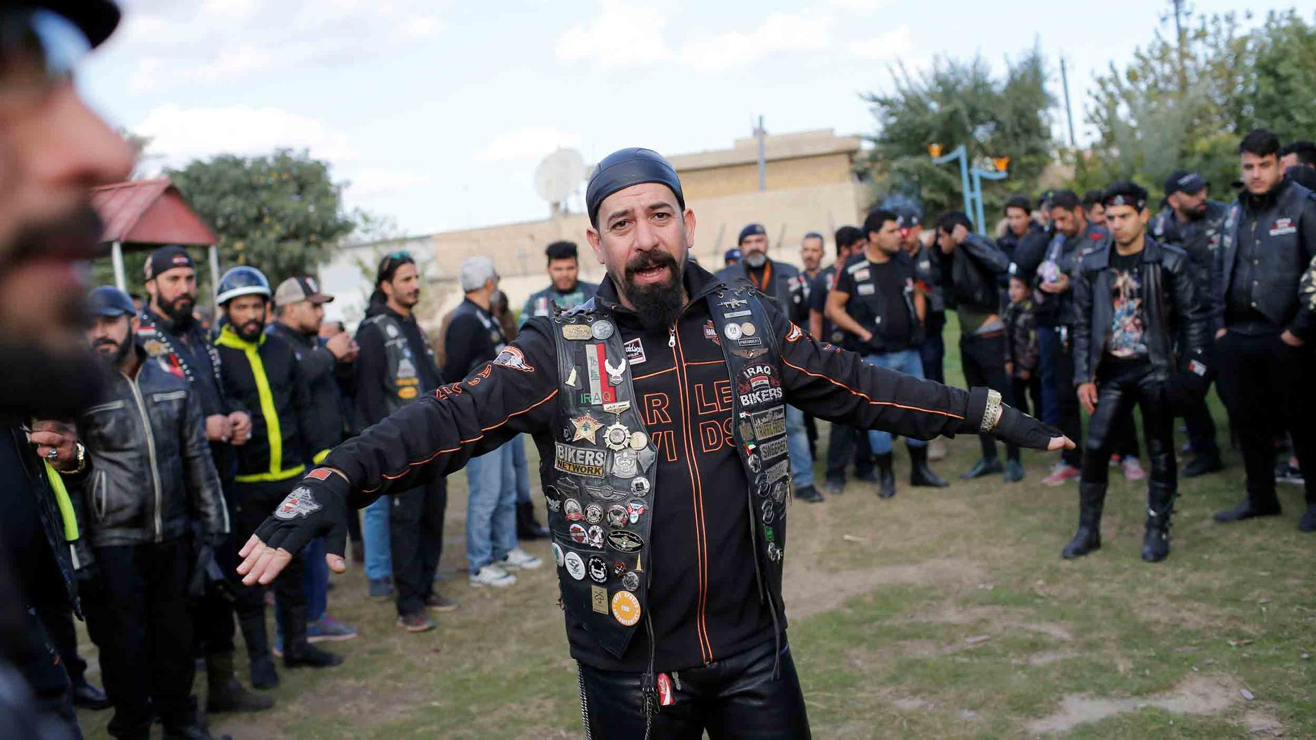 A man wearing all leather is surrounded by about three dozen others wearing similar clothing.