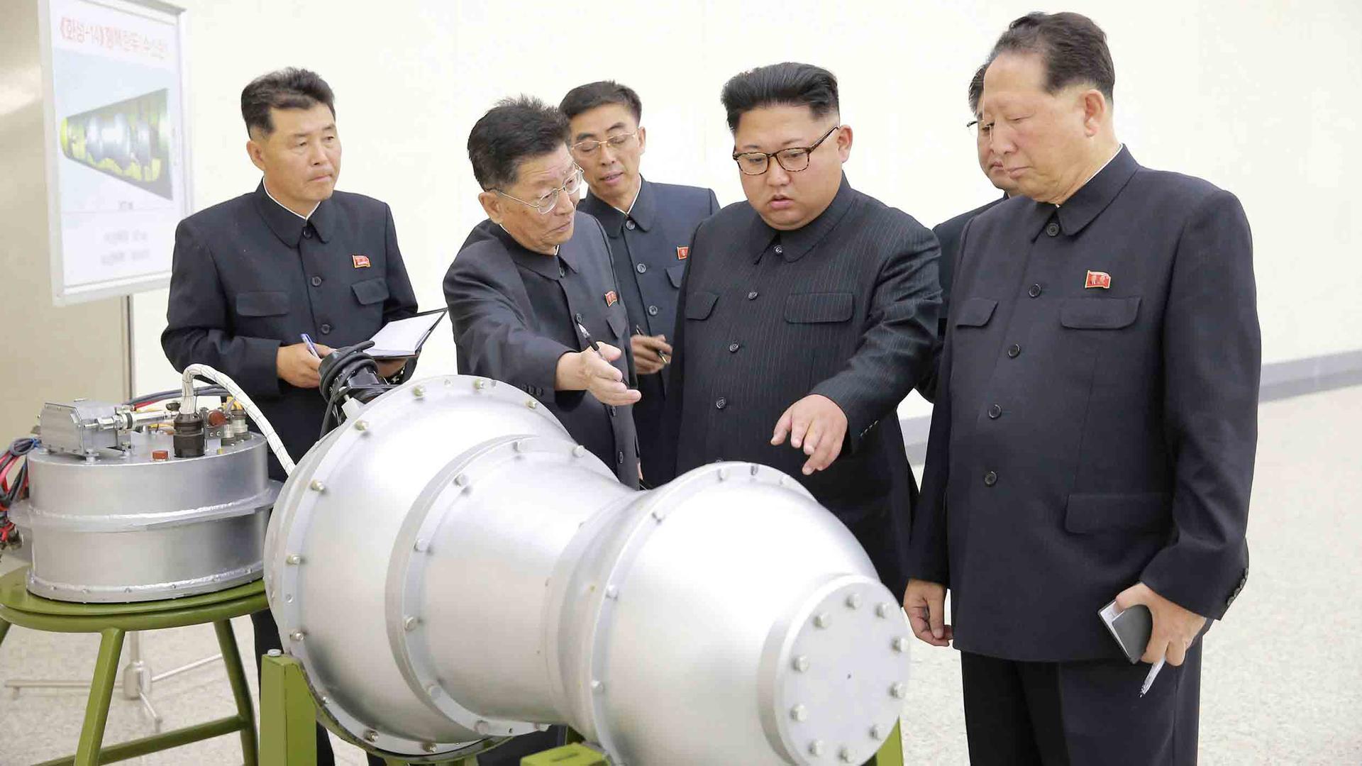 Kim Jong-un inspects a large metal piece of equipment with others around him. 