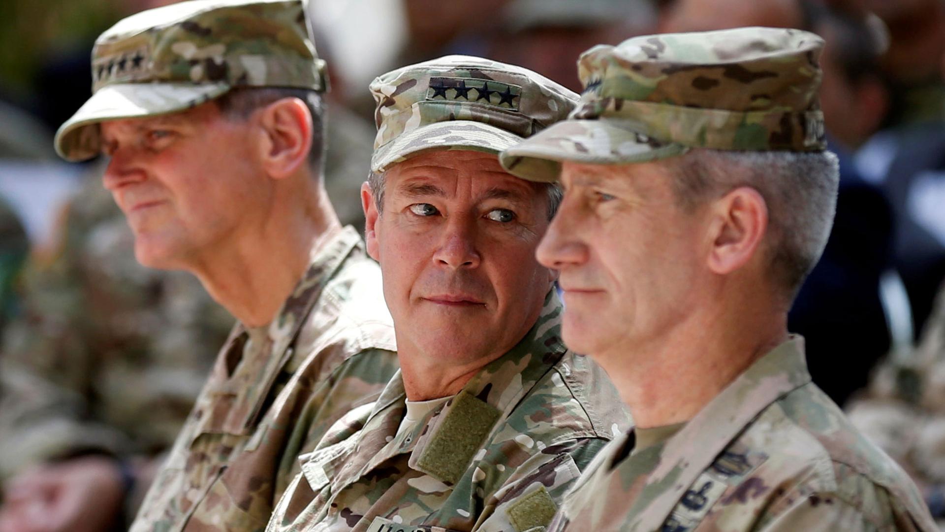US Army General Scott Miller is shown center looking over his left shoulder and wearing fatigues.