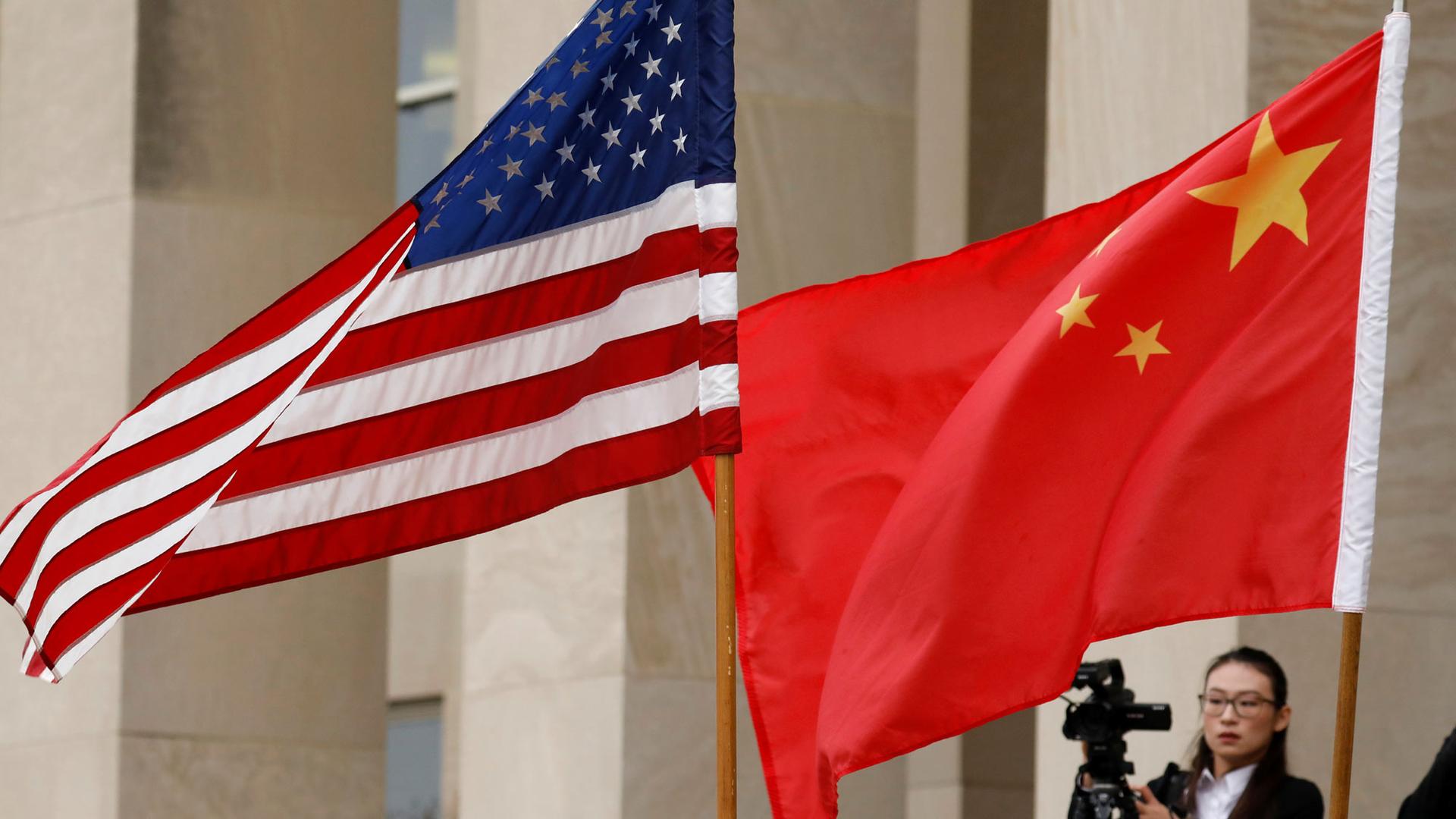 US and Chinese flags are showing flying with a photographer in the background at the Pentagon in Arlington, VA.