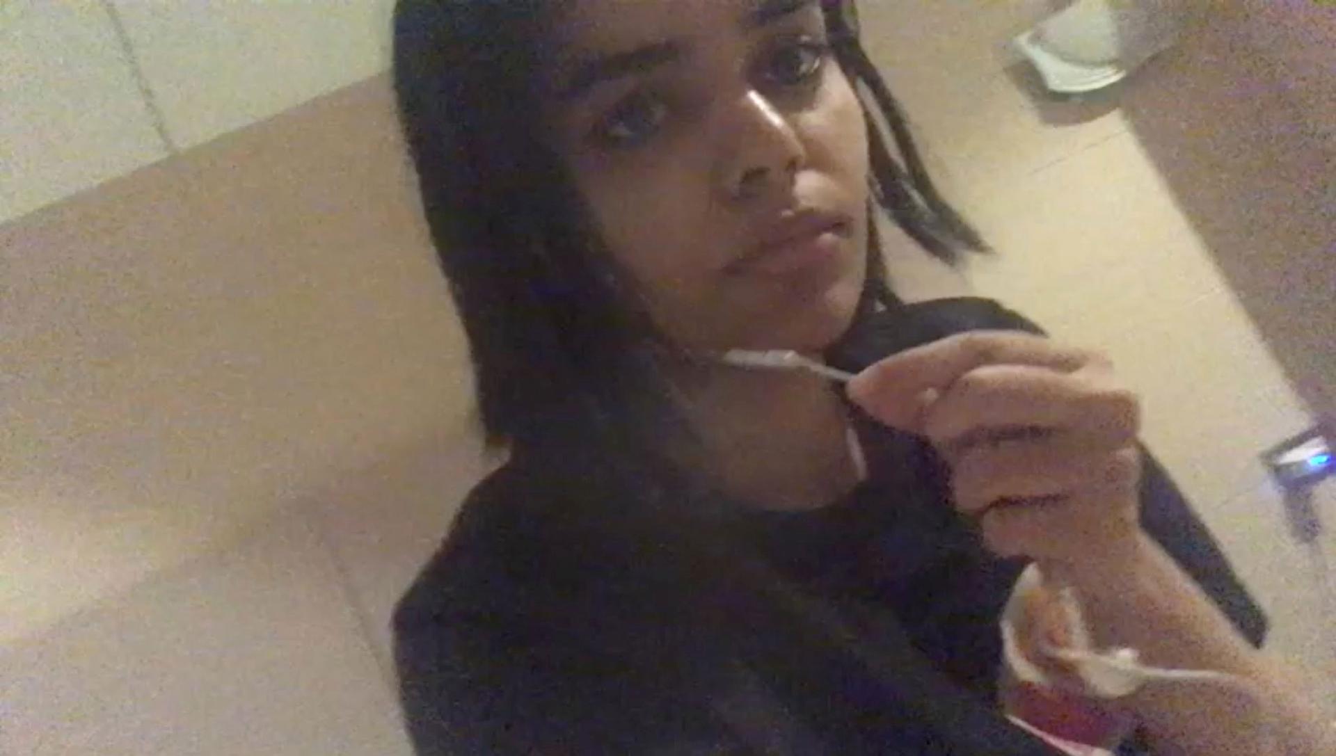 Rahaf Mohammed al-Qunun is shown in a still grainy still image taken from a video speaking into earbuds.