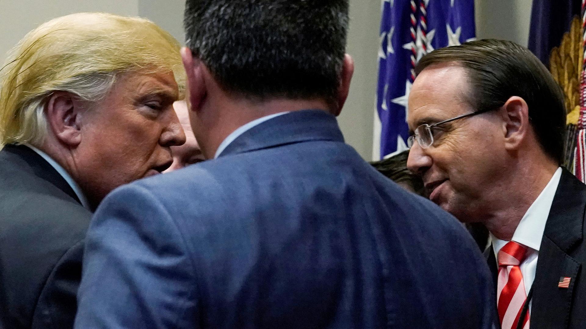 President Donald Trump is shown in this profile photography greeting Deputy US Attorney General Rod Rosenstein with flags in the background.