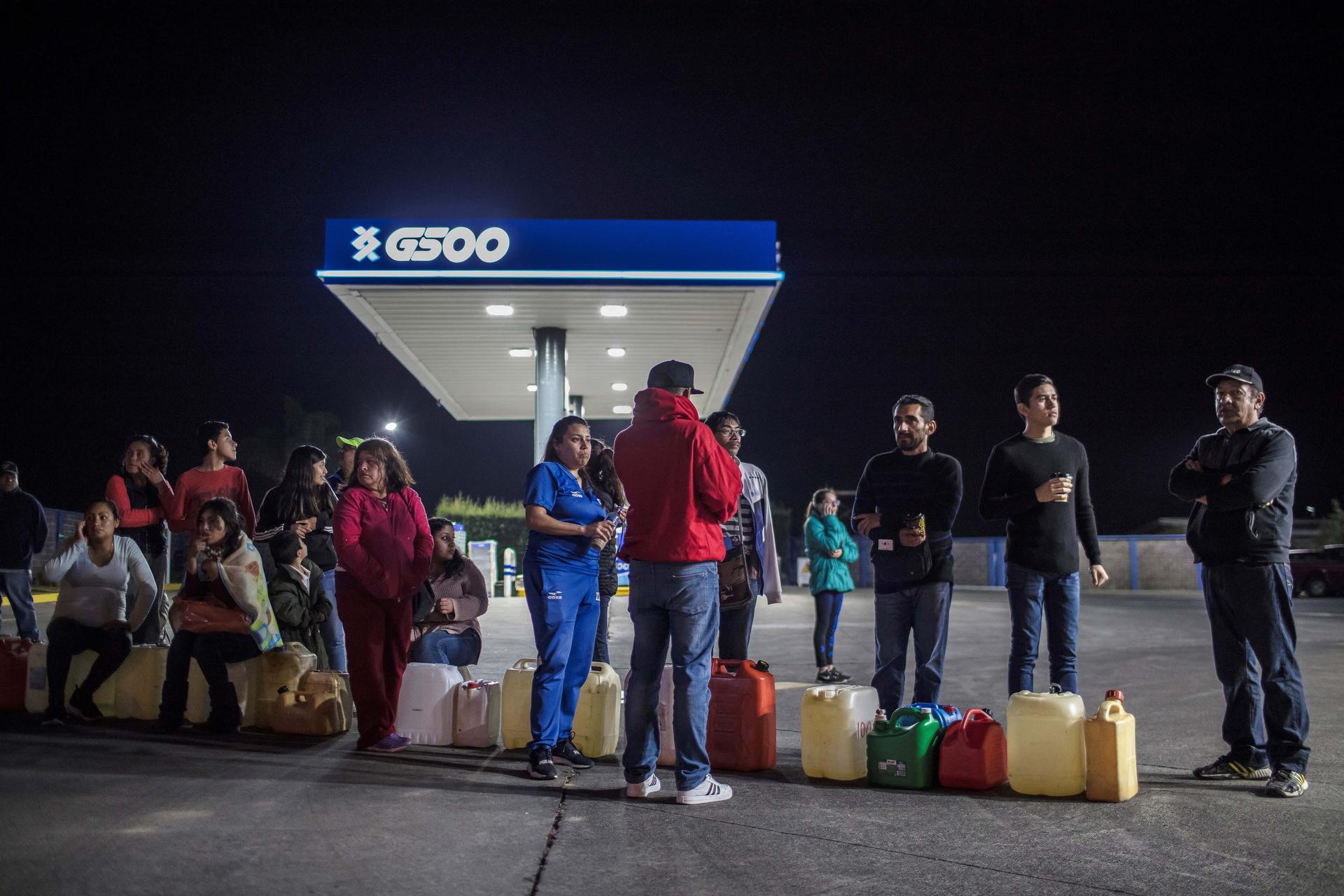 people wait in line in the dark for fuel