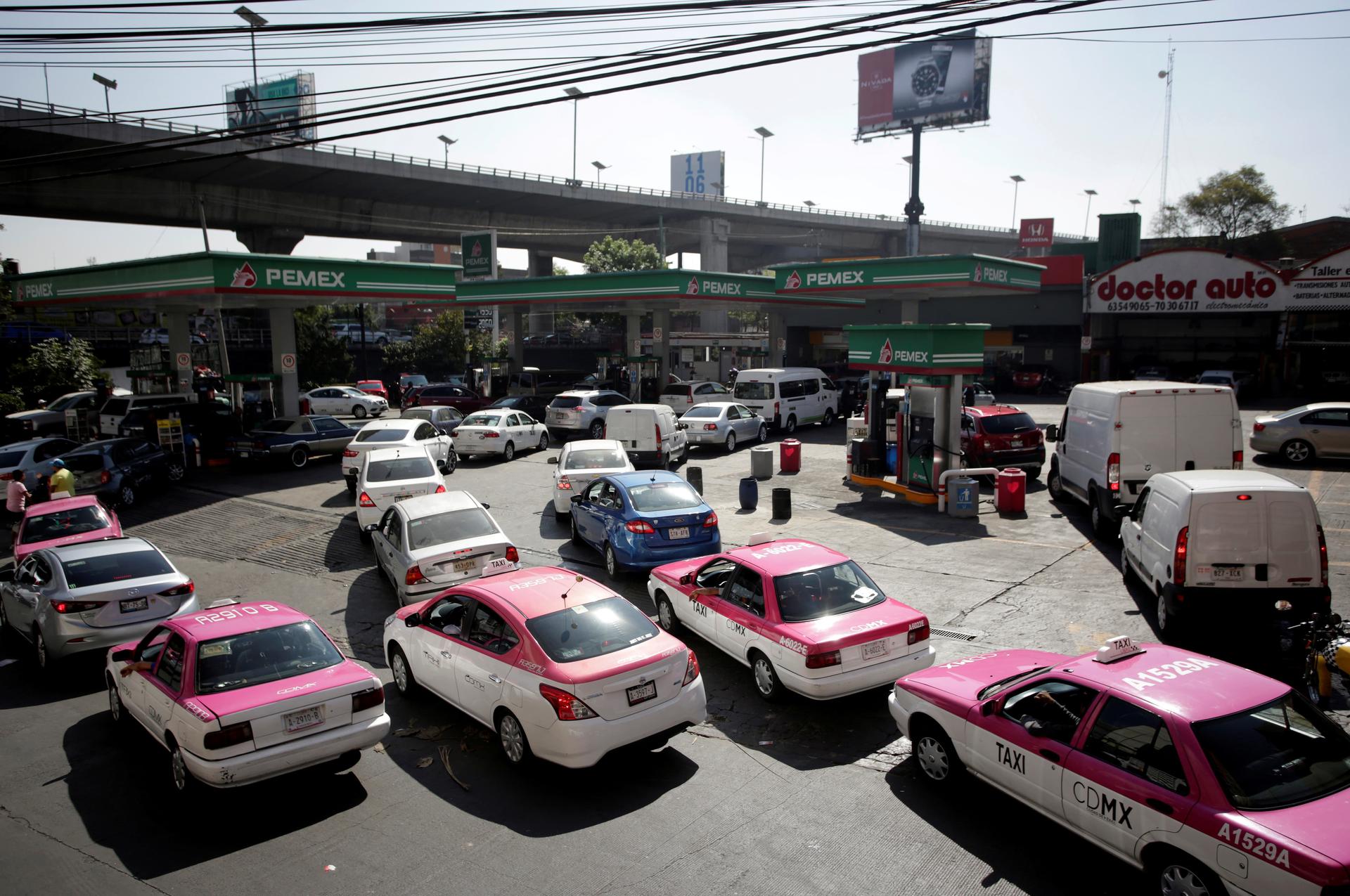 dozens and dozens of taxis line up around a fuel station