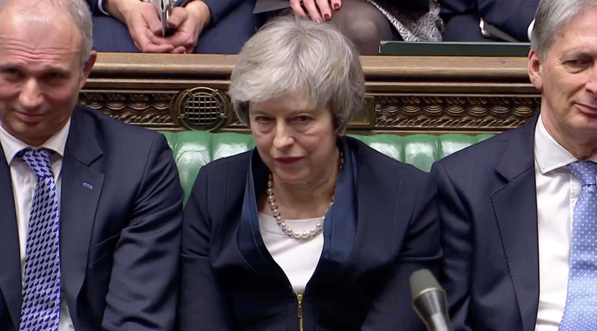 Prime Minister Theresa May sits down in Parliament with a grimace on her face